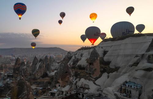 a group of hot air balloons flying over a mountain at Local Cave House Hotel in Göreme