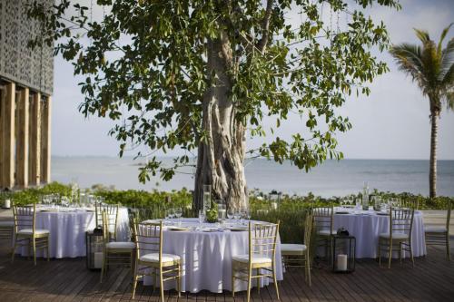 a table with white tables and chairs under a tree at NIZUC Resort & Spa in Cancún