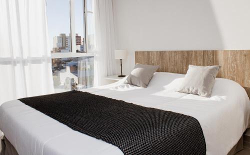 um quarto com uma grande cama branca e uma janela em CQ MITRE em Puerto Madryn