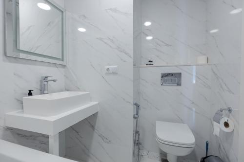 a white bathroom with a sink and a toilet at The SPOT apartments - Orbi Beach Tower in Batumi