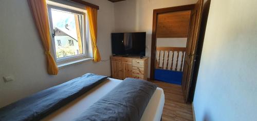 a bedroom with a bed and a tv and a window at Ferienwohnung Brader in Hallstatt