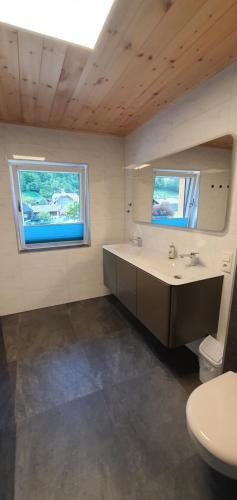 a bathroom with a sink and a toilet and two windows at Ferienwohnung Brader in Hallstatt