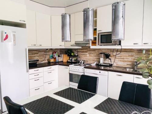 a kitchen with white cabinets and a table with chairs at Avara, ylellinen kaksikerroksinen huoneisto. in Jyväskylä
