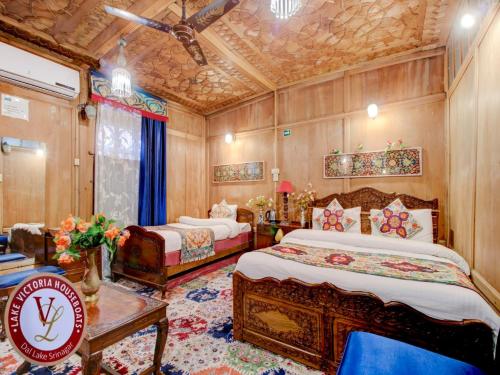 a bedroom with two beds and a table and a couch at Lake Victoria Houseboats in Srinagar
