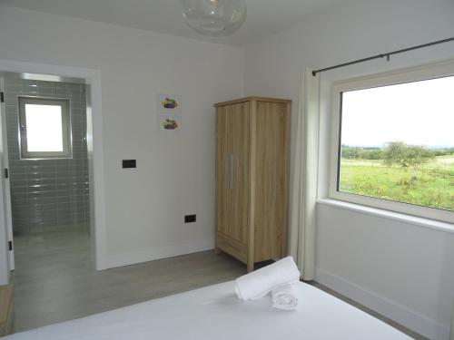 a white room with a window and a white bed at Kathleen's Carrowkeel Cottage in Sligo