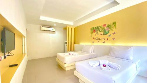 a hotel room with two beds and a tv at Kuapa Resort in Takua Pa