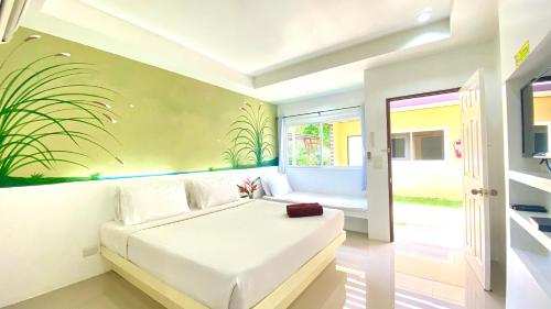 Kuapa Resort في Takua Pa: غرفة نوم مع سرير أبيض مع لوحة جدارية نباتية على الحائط