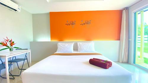 a bedroom with a white bed with an orange wall at Kuapa Resort in Takua Pa