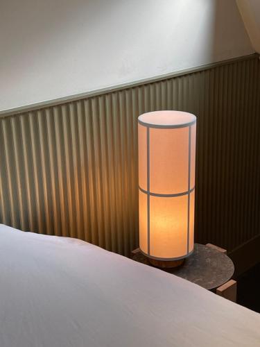 a lamp sitting on a table next to a bed at COMMUNE suites in Amsterdam