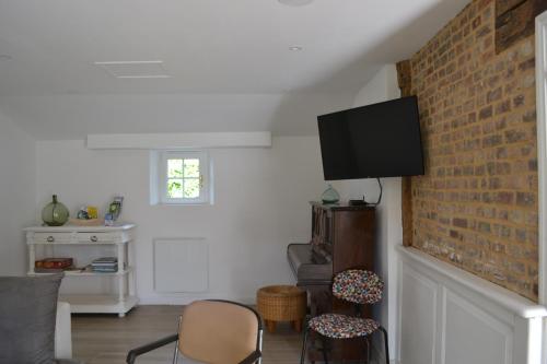 un salon avec une télévision sur un mur en briques dans l'établissement La clef des champs, à Doudeville