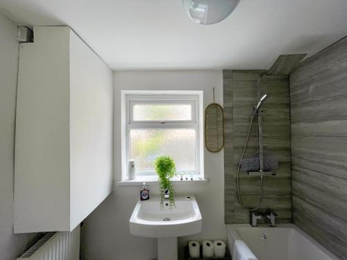 ein Bad mit einem Waschbecken, einem Fenster und einer Dusche in der Unterkunft Heritage House By MGroupSA - Free Parking in Nantyglo