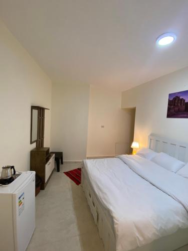 een slaapkamer met een groot wit bed en een dressoir bij Rose city inn in Wadi Musa