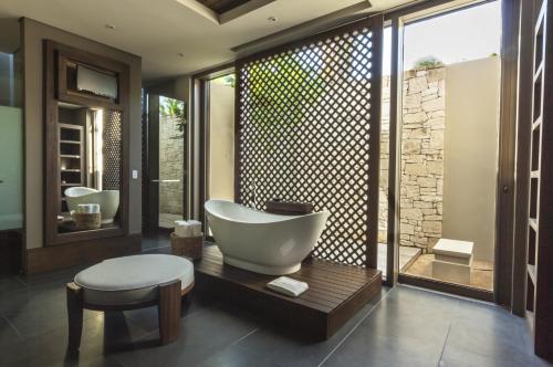 a bathroom with a tub and a sink and a chair at NIZUC Resort & Spa in Cancún