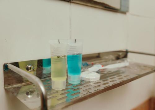 a bathroom sink with two cups on a counter at Tise Hotel in Kathmandu