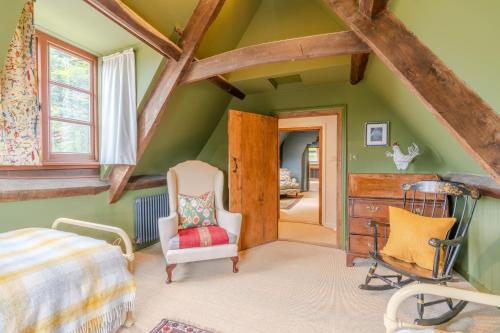 1 dormitorio con paredes verdes y techo con vigas de madera. en Locks Cottage, en Cheltenham