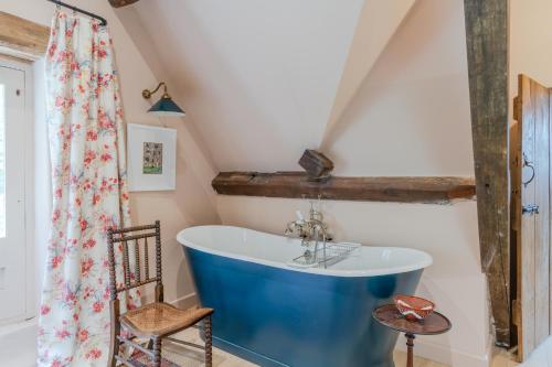 a bathroom with a blue tub in a attic at Locks Cottage in Cheltenham