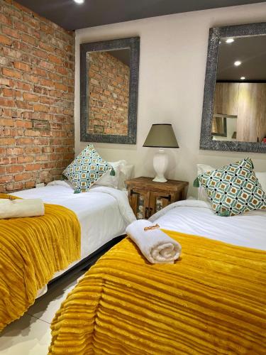 a bedroom with two beds and a brick wall at Tuscany Hill Manor in Hartswater