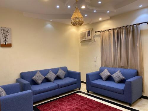 a living room with two blue couches and a chandelier at ABHASKY in Abha