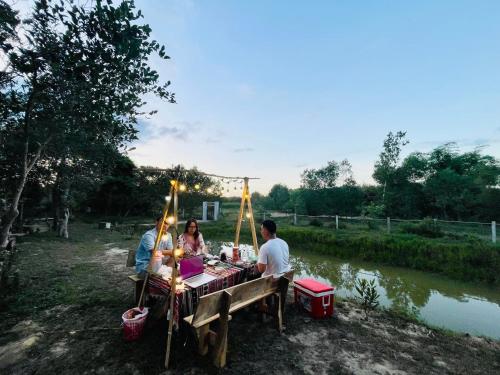 a group of people sitting at a picnic table by a river at Thôn Hoa Sen in Thôn Xuân Lỗ