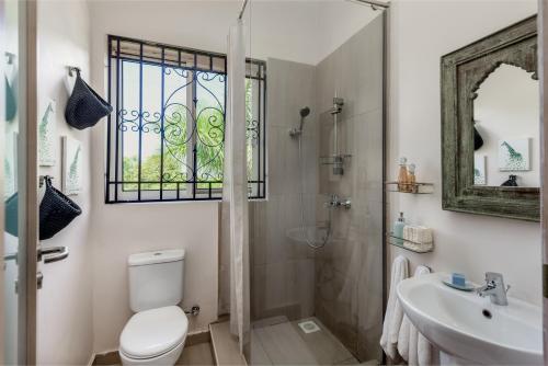 a bathroom with a shower and a toilet and a sink at Ewange - A Casa Mia in Kampala
