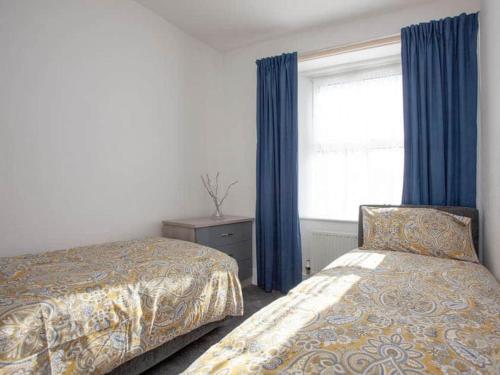 1 Schlafzimmer mit 2 Betten und einem Fenster mit blauen Vorhängen in der Unterkunft Suzie's Pad Torquay Devon in Torquay