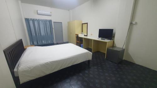 um quarto com uma cama e uma secretária com um computador em Monta Apartment em Bangsaen