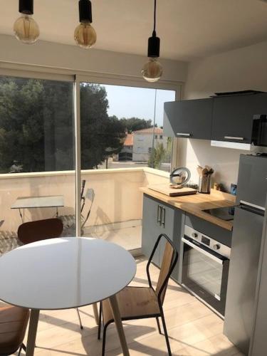 - une cuisine avec une table et une table et des chaises blanches dans l'établissement Superbe Studio tout confort Carro - Côte Bleue, à Martigues