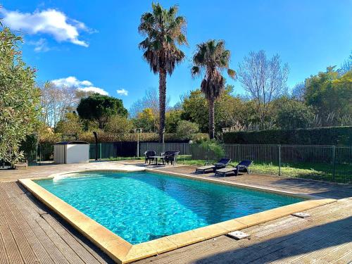 - une piscine avec 2 chaises et 2 palmiers dans l'établissement Bellevue Maison de pêcheur, à Cogolin