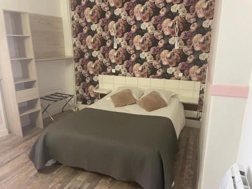 a bedroom with a bed with a floral wallpaper at Hotel Au Chapon Fin in Poitiers