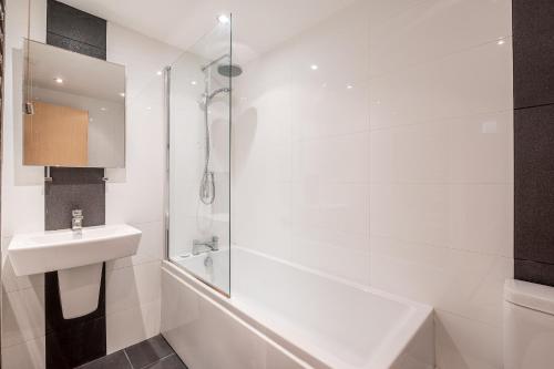 La salle de bains blanche est pourvue d'un lavabo et d'une douche. dans l'établissement 4 Crambeck Court, à York