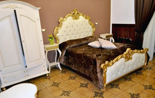 a bedroom with a white bed with a gold frame at Hotel des Artistes in Naples