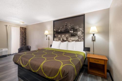 a hotel room with a bed and a picture on the wall at Super 8 by Wyndham Kansas City Airport North in Kansas City