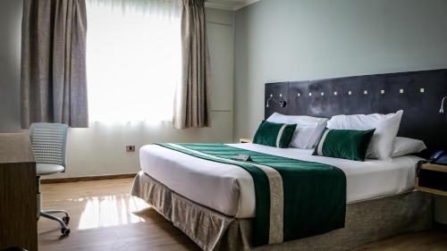 um quarto com uma cama grande e almofadas verdes e brancas em Ecohotel Talca em Talca