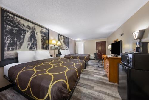 a hotel room with two beds and a flat screen tv at Super 8 by Wyndham Kansas City Airport North in Kansas City