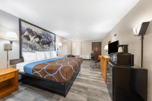 a hotel room with a bed and a flat screen tv at Super 8 by Wyndham Kansas City Airport North in Kansas City