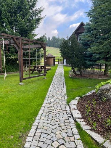 a stone walkway in a yard with a pavilion at Penzion Koucký in Bedřichov