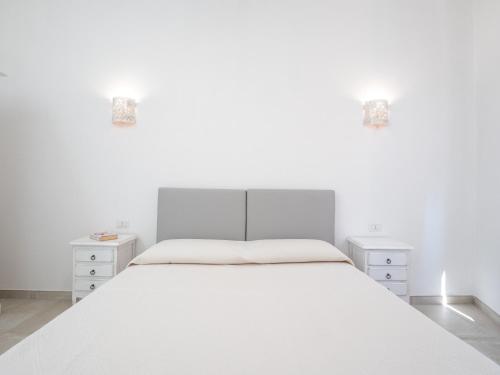 a white bedroom with a large white bed and two night stands at Affittacamere Solki in SantʼAntìoco