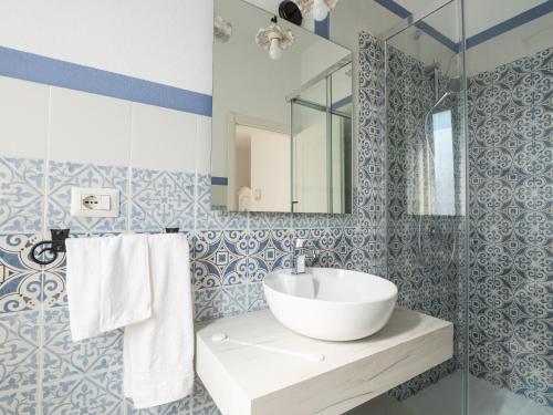 a bathroom with blue and white tiled walls and a sink at Affittacamere Solki in SantʼAntìoco