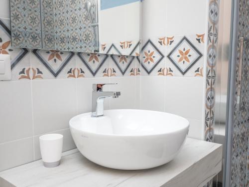 a white sink in a bathroom with tiles at Affittacamere Solki in SantʼAntìoco