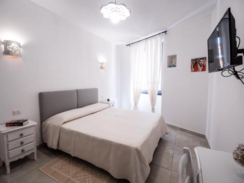 a white bedroom with a bed and a television at Affittacamere Solki in SantʼAntìoco