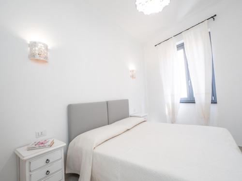 a white bedroom with a bed and a window at Affittacamere Solki in SantʼAntìoco