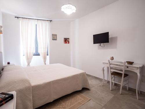 a bedroom with a bed and a desk and a television at Affittacamere Solki in SantʼAntìoco