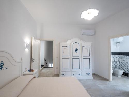 Habitación blanca con cama y baño. en Affittacamere Solki, en SantʼAntìoco