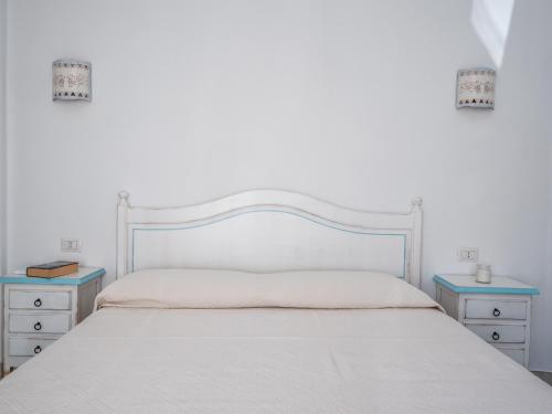 a bedroom with a white bed with two night stands at Affittacamere Solki in SantʼAntìoco