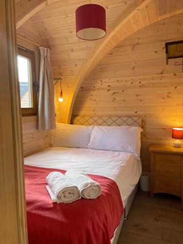 a bedroom with a bed in a log cabin at Squirrel Glamping Pod School House Farm in Leighton