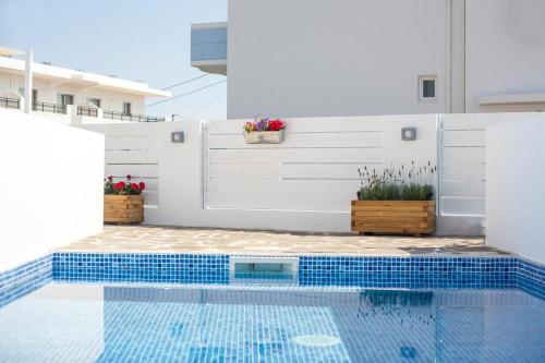 a swimming pool with a white wall and a blue tile floor at Alexander Studios & Suites - Adults Only in Faliraki