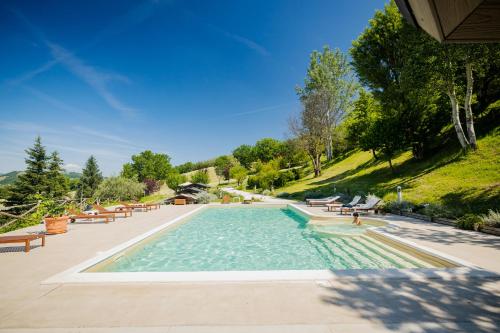 a swimming pool with benches and trees and a hill at L'Incanto dei Sibillini in Cessapalombo