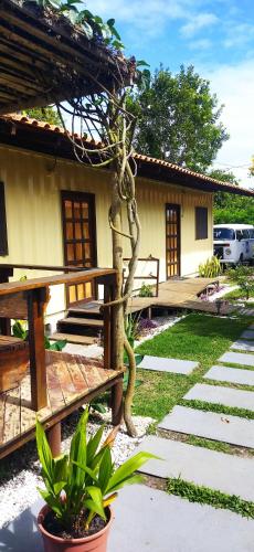 a house with a bench and a tree in the yard at Abrolhos Dive Inn in Caravellas