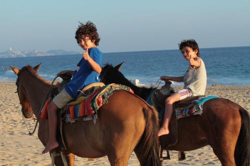 two children riding on horses on the beach at Hotel Gilda in Coyuca