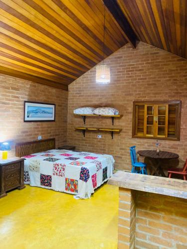 a bedroom with a bed and a table in a room at Chale Vista Bela - Gonçalves c/ vista p/ Montanhas in Gonçalves